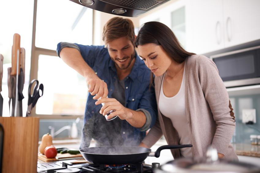 A young couple making dinner together at home